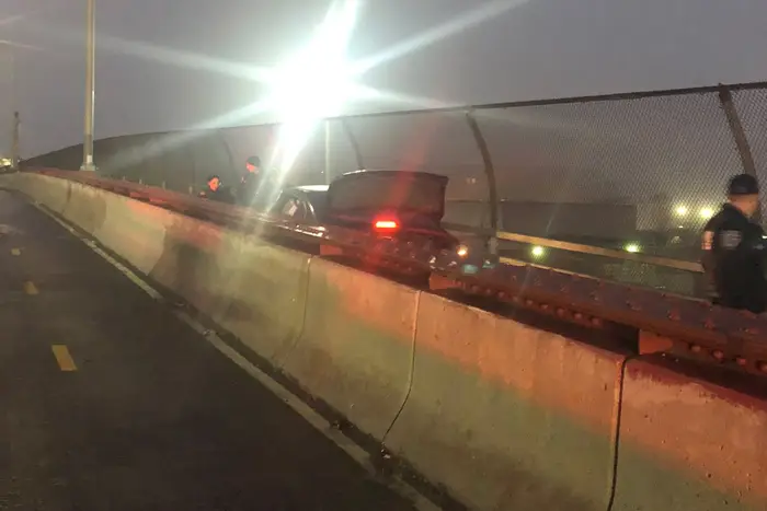 A car stuck in the pedestrian path of the Pulaski Bridge at night